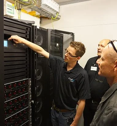 Engineers reviewing rack-mounted CDU monitoring and management interface.
