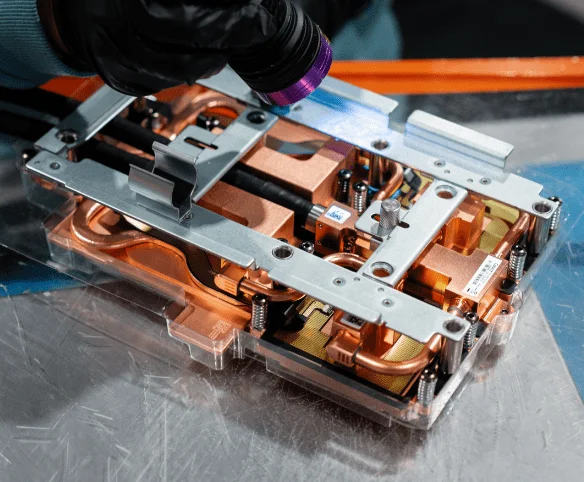 A technician using a UV light to inspect a copper coldplate assembly for CoolIT Systems.