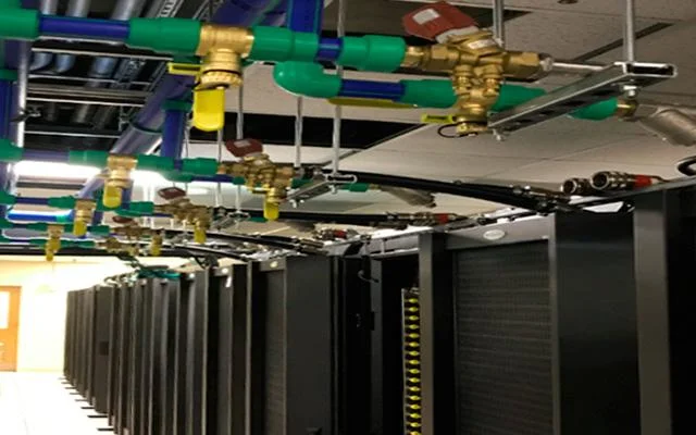 High-density HPC data centre racks with overhead liquid cooling piping supplying coolant to servers.
