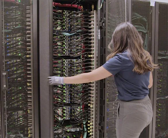 Technician servicing liquid-cooled data centre rack with direct-to-chip cooling.