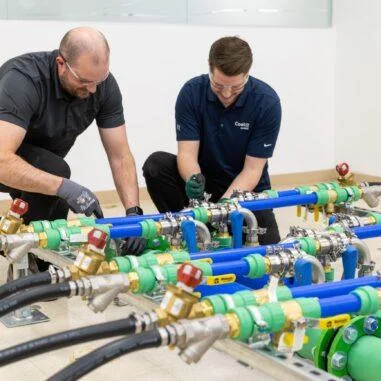 Engineers assembling liquid cooling manifold system with industrial piping