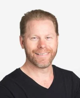 A professional headshot of Brydon Gierl, smiling and wearing a black V-neck t-shirt.