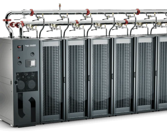 A row of eight black server cabinets connected to an overhead manifold system made of polished stainless steel with red-handled valves.