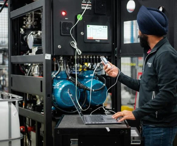 Technician testing CoolIT CDU control panel and pumps on a manufacturing floor