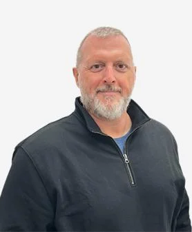 A professional headshot of Scott Hudson, smiling and wearing a black quarter-zip pullover.